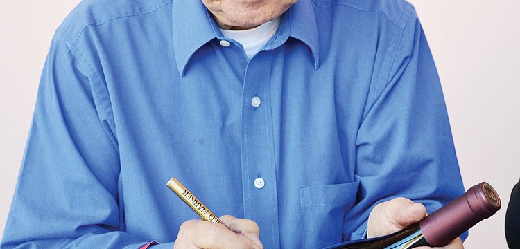 Robert Hall autographs one of his wines at Forks and Cooks Food and Wine Festival.