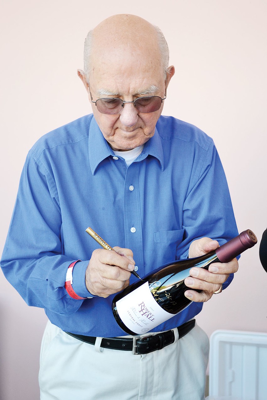 Robert Hall autographs one of his wines at Forks and Cooks Food and Wine Festival.