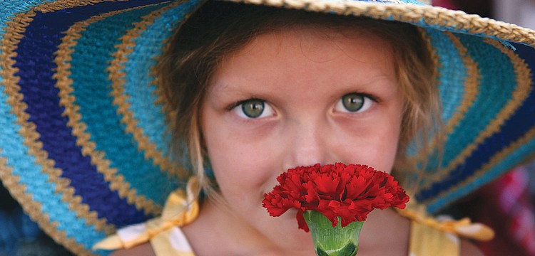 Mira Carpenter, 4, smells the red carnation she was given at the Sarasota Farmers Market.