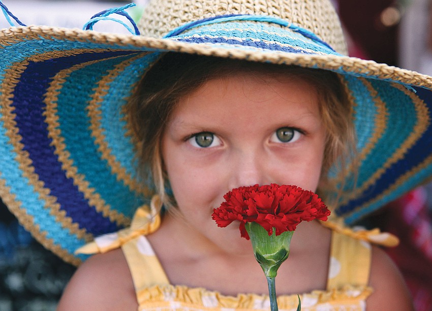 Mira Carpenter, 4, smells the red carnation she was given at the Sarasota Farmers Market.