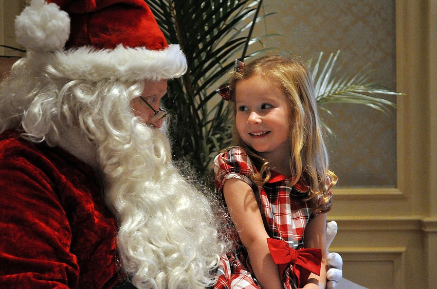 Norah Meyer, 3, smiles at Santa as he talks to her about what she might like for Christmas Sunday, Dec. 16, during the Breakfast with Santa event at the Ritz Carlton.