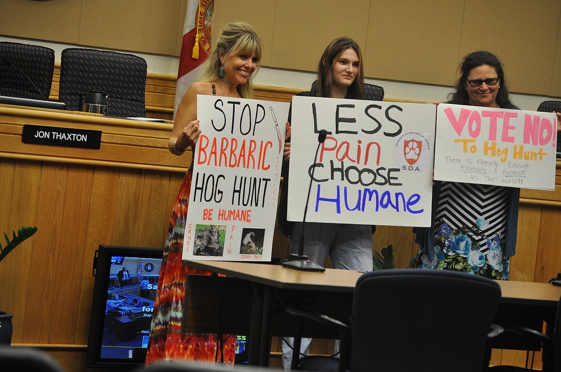 Opponents of the Deer Prairie Creek Preserve hog hunt brought signs to a July 10 Sarasota County Commission meeting.