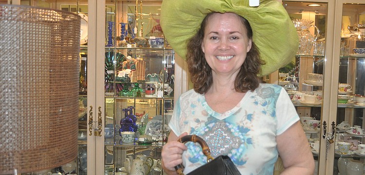 Stephanie Claussen, owner of Steffâ€™s Stuff Antiques, models a sun hat (â€œkeeps the wrinkles away,â€ she says) and a vintage pocketbook from Saks Fifth Avenue.