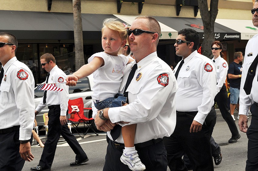 Glenn Snyder carries his daughter, Peyton, 3 for the annual Sarasota Memorial Day Parade, May 28, in downtown.