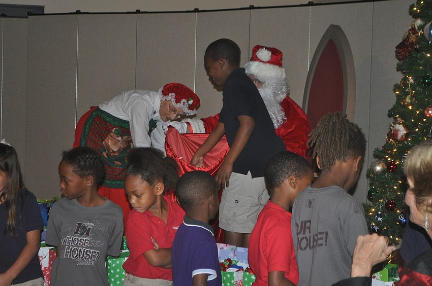 Ginny Dreher and Andy Rauch, dressed as Mr. and Mrs. Clause, distribute gifts to the children.