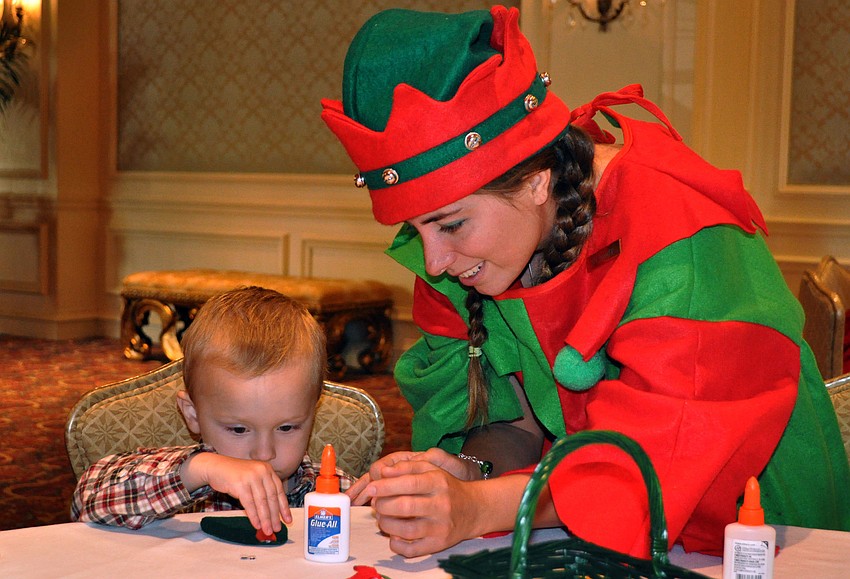 Elf Mandy helps Charlie Meyer, 2, make a candy cane mouse.