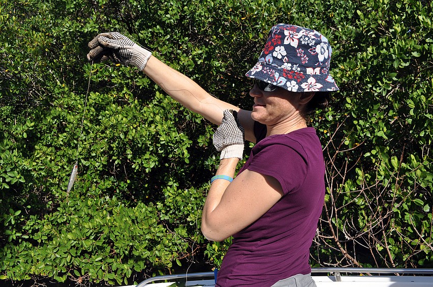 Jennifer Moore pulls a large about of fishing line with a fishing lure attached out of a tree.
