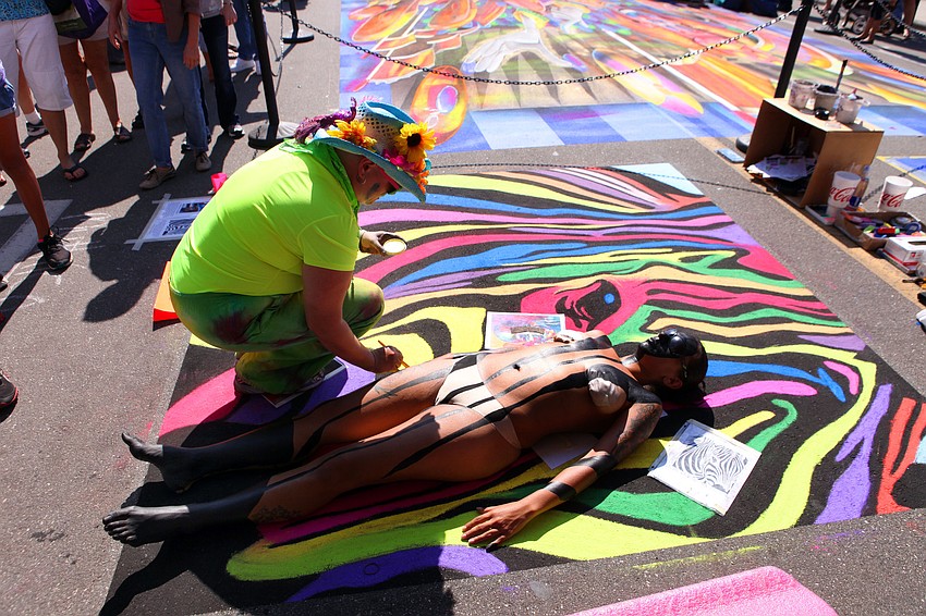 Mythica Von Griffyn paints Gina Lopez into her colorful chalk piece of a zebra Saturday, Nov. 3, on Pineapple Avenue.