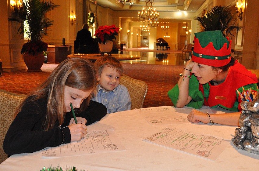 Marissa Govic, 8, works on writing her letter to Santa while Elf Morganna helps Jack Govic, 5, come up with things to put on his list to Santa.