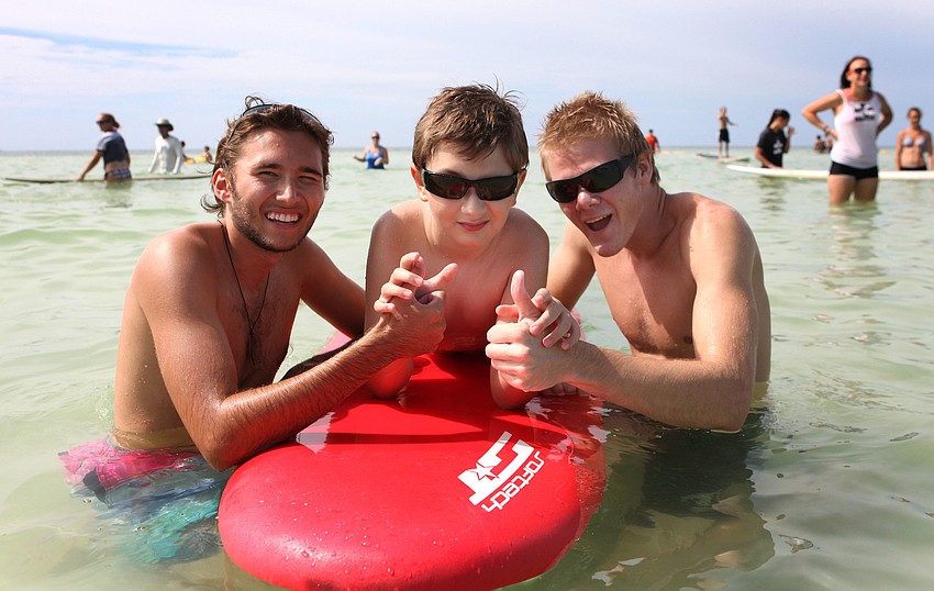 Alex Miller and Seton Morgan give thumbs up with Noah Burg, 9, Saturday, Sept. 15 during Hang 10 for Autism at Siesta Key Public Beach.