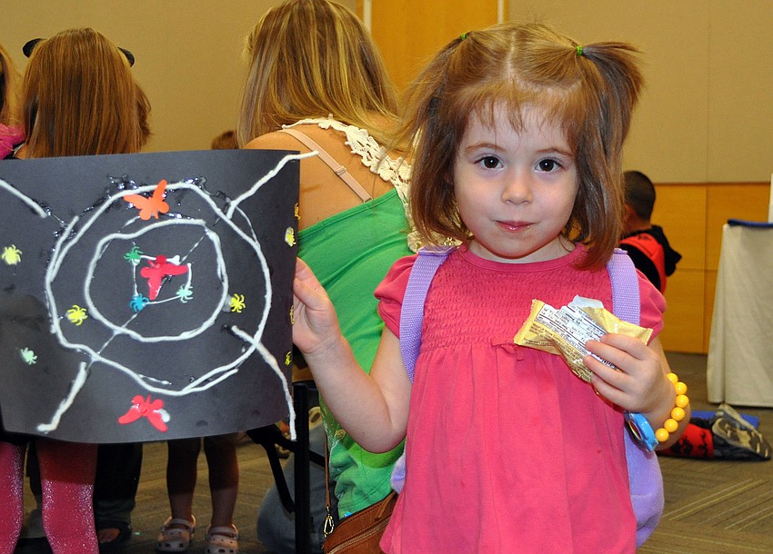 Lea Brunke, 2, shows off the spider web craft she made Wednesday, Oct. 24, at Selby Public Libraryâ€™s Halloween Party.