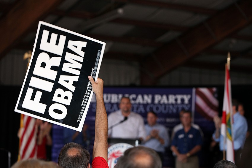 A member of the crowd waves a â€œFire Obamaâ€ sign during the rally Saturday, Nov. 3, at Dolphin Aviation.