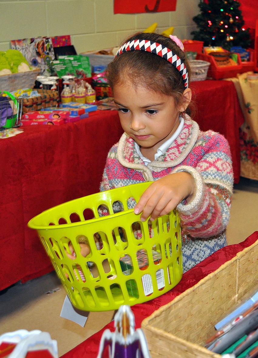 Anna Tursonva, 7, walks around the Holiday House filling her basket with gifts for her friends and family.