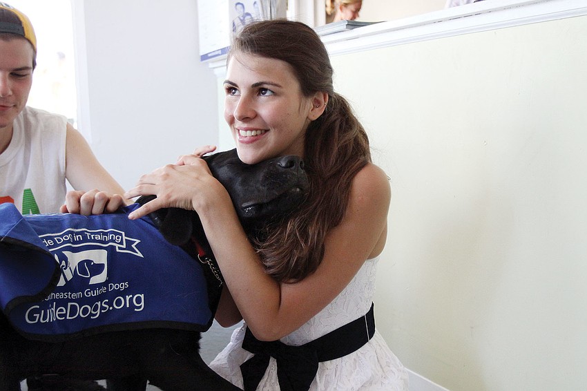 Doc snuggles into Beatriz Urrutia during Puppy Love at Southeastern Guide Dogs Sarasota.