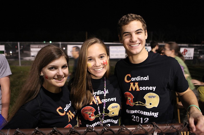 Seniors Jennifer McElroy, Emily Rzonac and Kyle Leicht have fun cheering on the Cougars during Cardinal Mooneyâ€™s homecoming game Friday, Oct. 12.