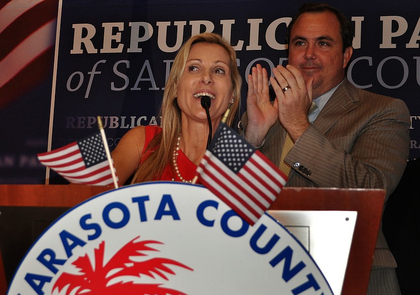 Alex Miller smiles and acknowledges her win on stage along side Joe Gruters.