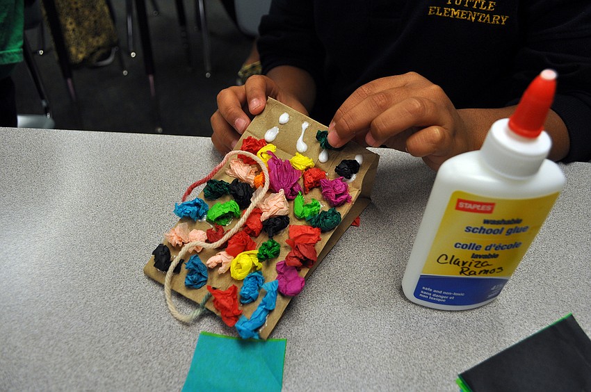 Brian Quintanilla adds colorful pieces of tissue paper to his piÃ±ata.