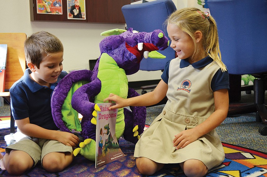 Liam Lizotte and Kate Kempton play with Principal Steve Dragon's stuffed animal dragon.