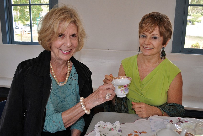 Susan Rawson and Cheryl Gross hold up their teacups.