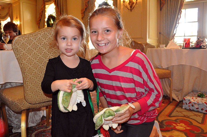 Samantha Chessler, 2, and Lexy Melone, 11, show off the stuffed animal turtles they received from Santa Sunday, Dec. 16, at the Breakfast with Santa event at the Ritz Carlton.
