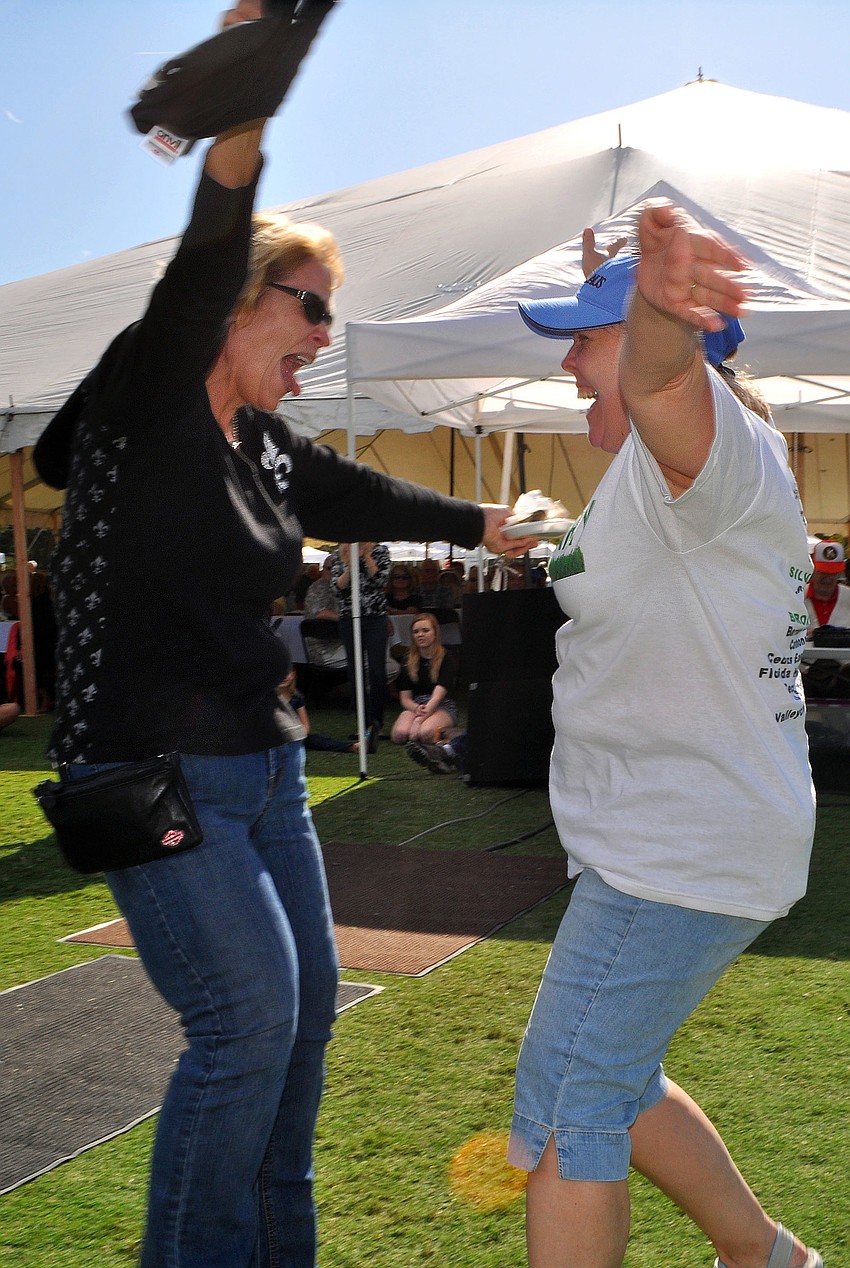 Jo Ann Mixon and Sandi Henley jump for joy and go to hug one another after winning the big raffle prize of $20,000.