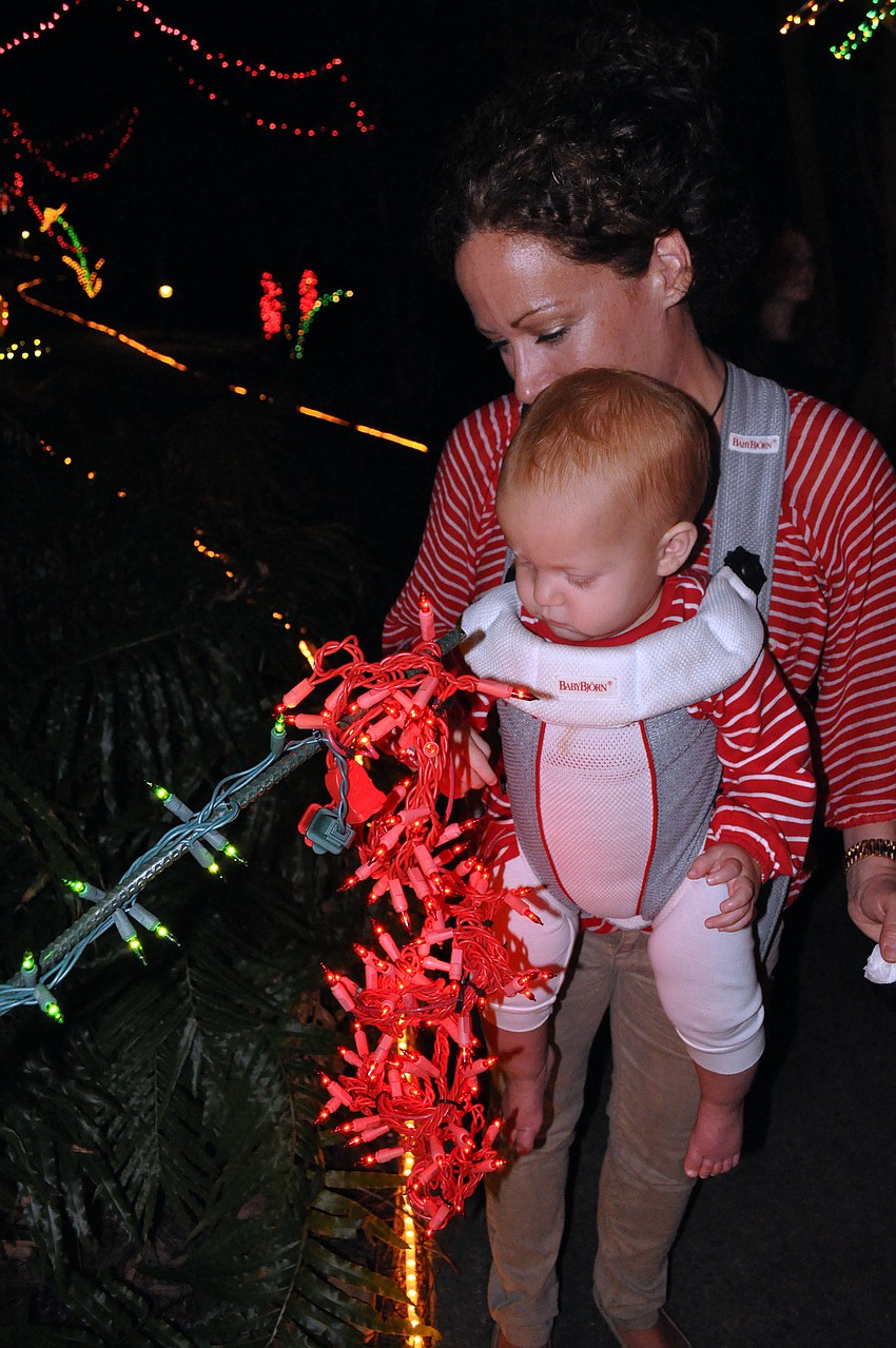 Mindy Rollins stops and letâ€™s her daughter, Eve, 1, look intently at one of the light displays.