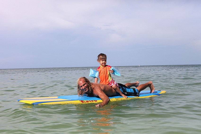 Pat Ryan paddles around with Gabe Bishop, 3, on his back.