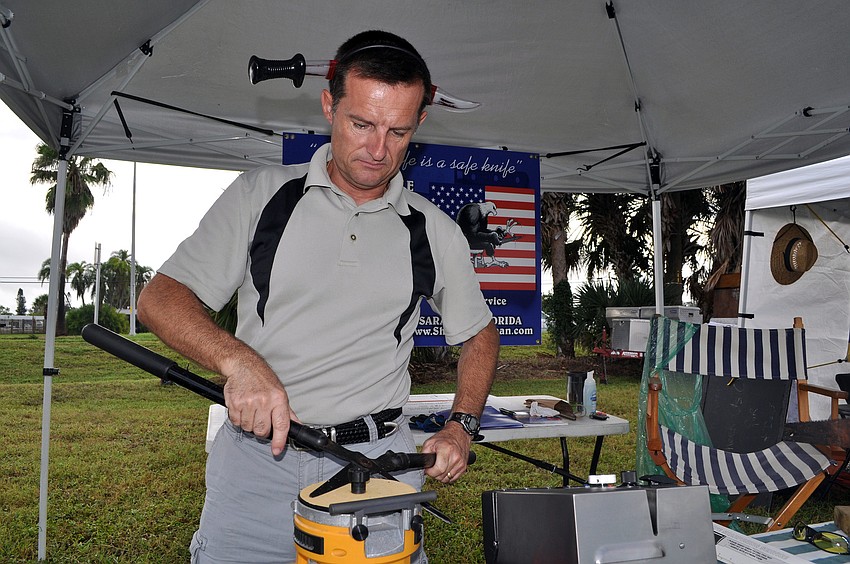 Thierry Rouillard wears a headband making it look like a knife is going through his head as he works on sharpening some scissors.
