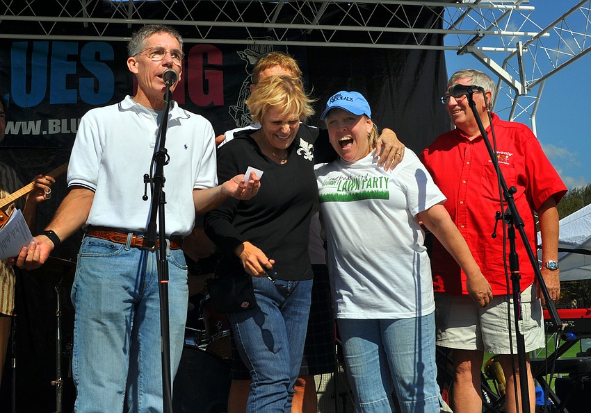 Matt Walsh and John Wild stand on stage with two of the four owners of the winning $20,000 ticket, Jo Ann Mixon and Sandi Henley, Saturday, Nov. 17, at the Longboat Key Gourmet Lawn Party.