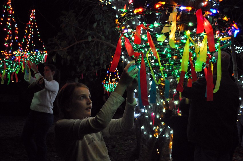 Annie Shiparski, 10, ties her wish onto one of the baskets hanging from the â€œwishing treeâ€, also known as a Bo tree.