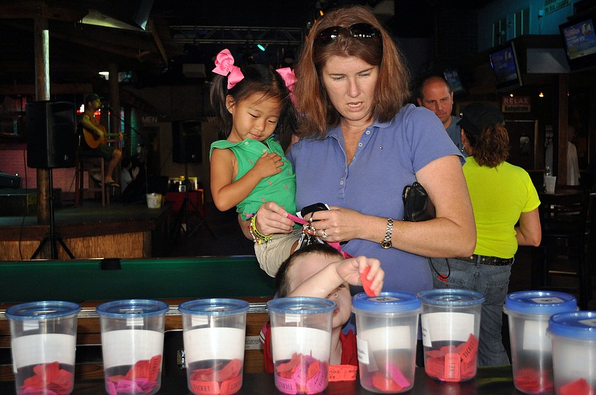 Ellen Barry holds her daughter, Anna Cate, 2, as she watches her son, Michael, 4, put a ticket into one of the raffle containers.