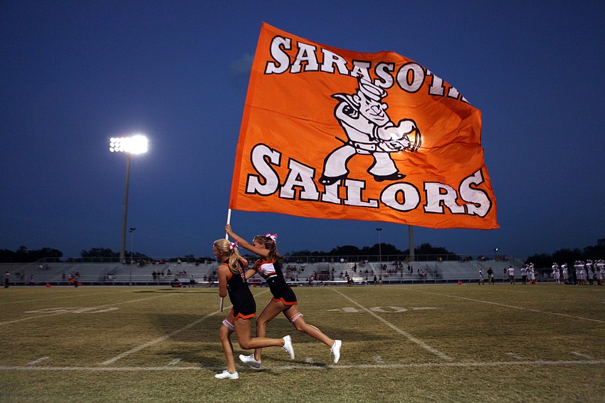 Sailor cheerleaders run up and down the field with a large Sarasota Sailors flag before the game.