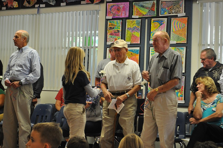 Students present veterans with carnations.