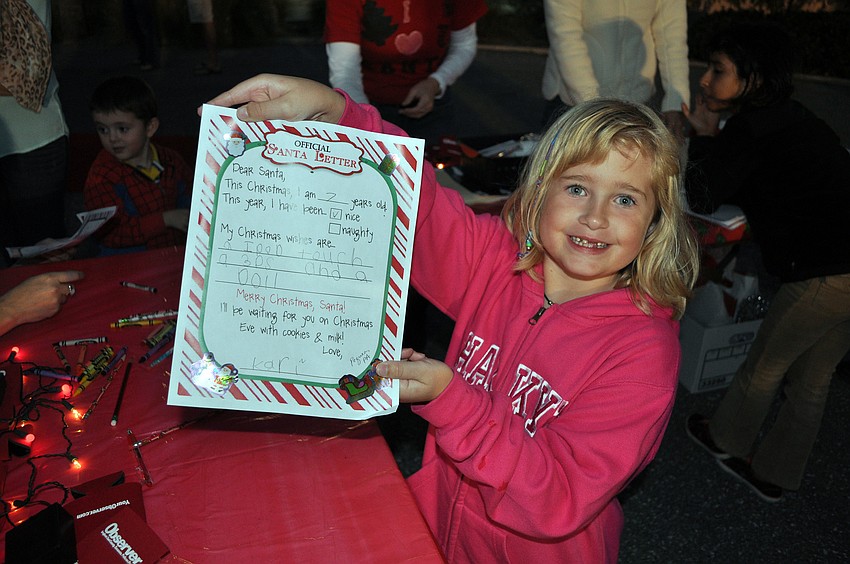 Kari Anderson, 7, shows off the letter she wrote to Santa Saturday, Nov. 24, during Siesta Keyâ€™s Light Up the Village parade.
