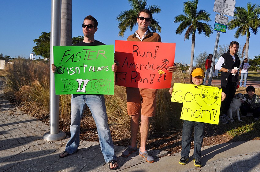 Alex Alston, Steven Piskoty and Daniel Desear, 5, hold up signs to cheer on Amanda Desear during the 2nd Annual Achieva Reindeer Trot Saturday, Dec. 1, at Payne Park.