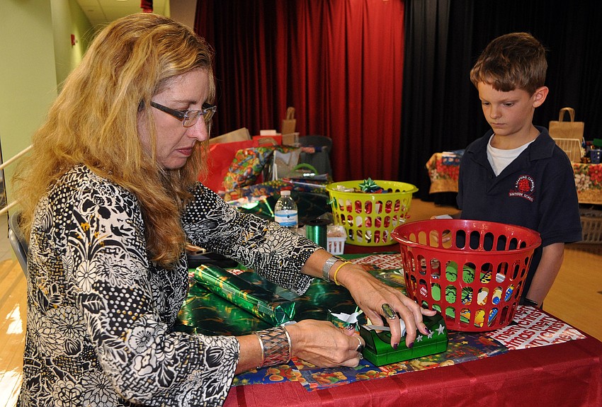 Camille Chapman helps wrap David Huberâ€™s, 7, gifts that he bought for his family at the Holiday House Tuesday, Dec. 4, at Southside Elementary.