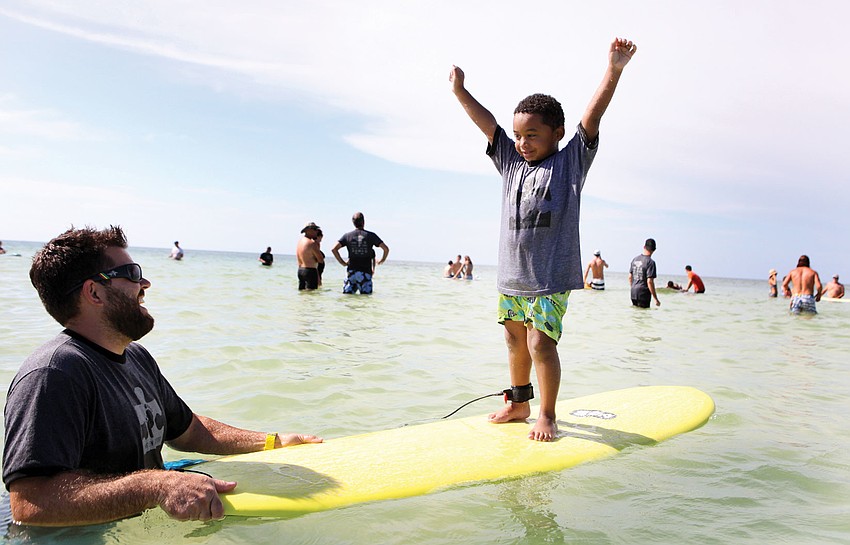 Mark Weeks laughs as Caiden Woodworth, 5, raises his arms up in the air victoriously, Sept. 15, during Hang 10 for Autism on Siesta Key Beach.
