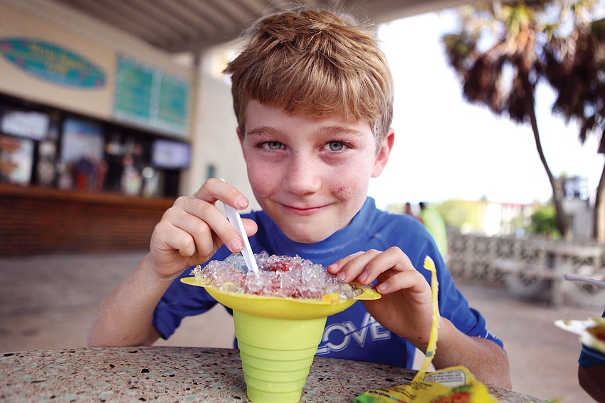 Jake Nicolson, 8, enjoys a snow cone while hanging out underneath the pavilion at Siesta Key Beach, Oct. 7.