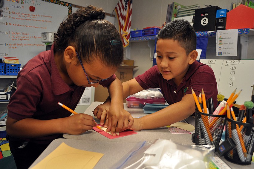 Jorge Frayre helps Jazlynn Williams trace a piece that will make up part of her Santa Christmas card.