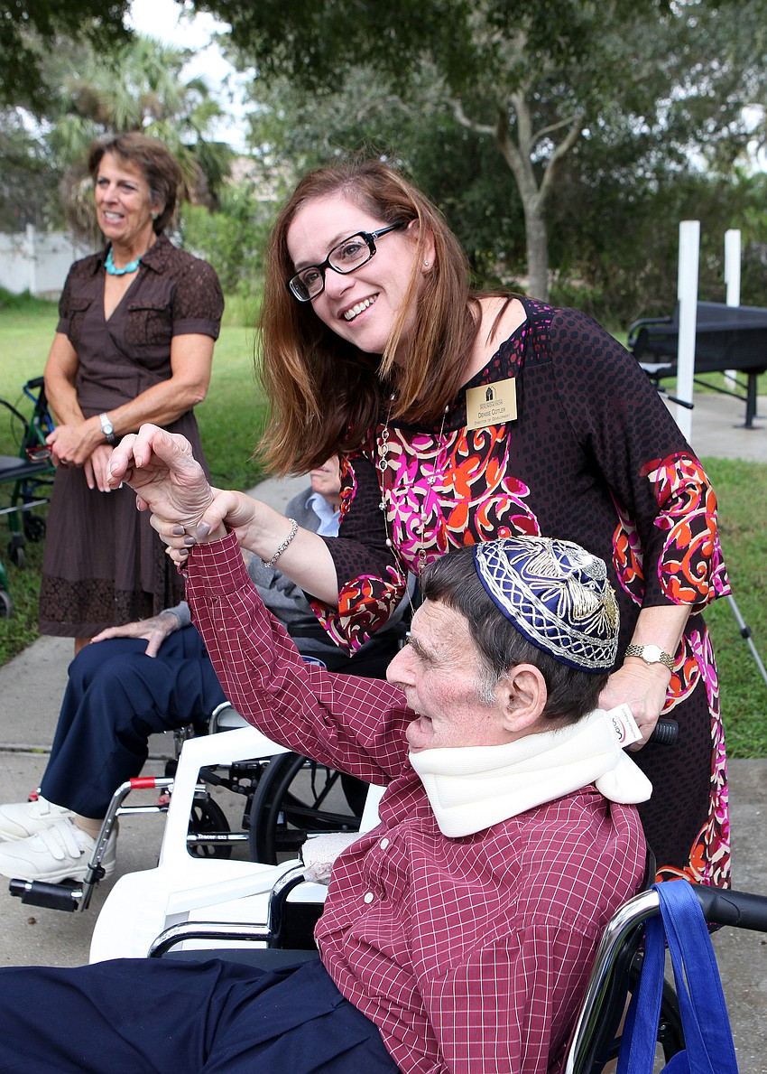 Denise Cotler helps her father, Jacob Bernholz, raise his hand to collect a sin Tuesday, Sept. 18 during the Tashlich ceremony at the Anchin Pavilion.
