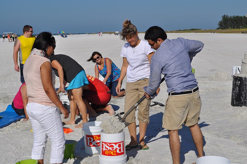 Mohit Gupta fills a bottomless bucket with sand to create the base of a sand castle.