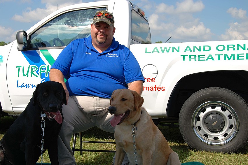 Brian Lalmond and his two labs, Johny Cash and Willie Nelson, relax in the shade while enjoying the event.