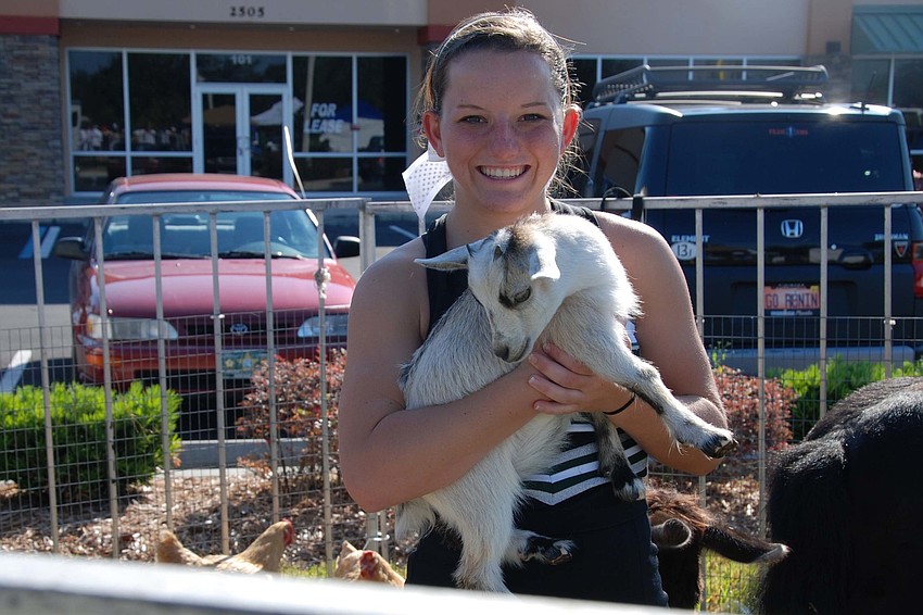 Lakewood Ranch High School's varsity cheerleader, Samantha Hannabass, smiles for a picture as she cuddles a goat from the petting zoo.