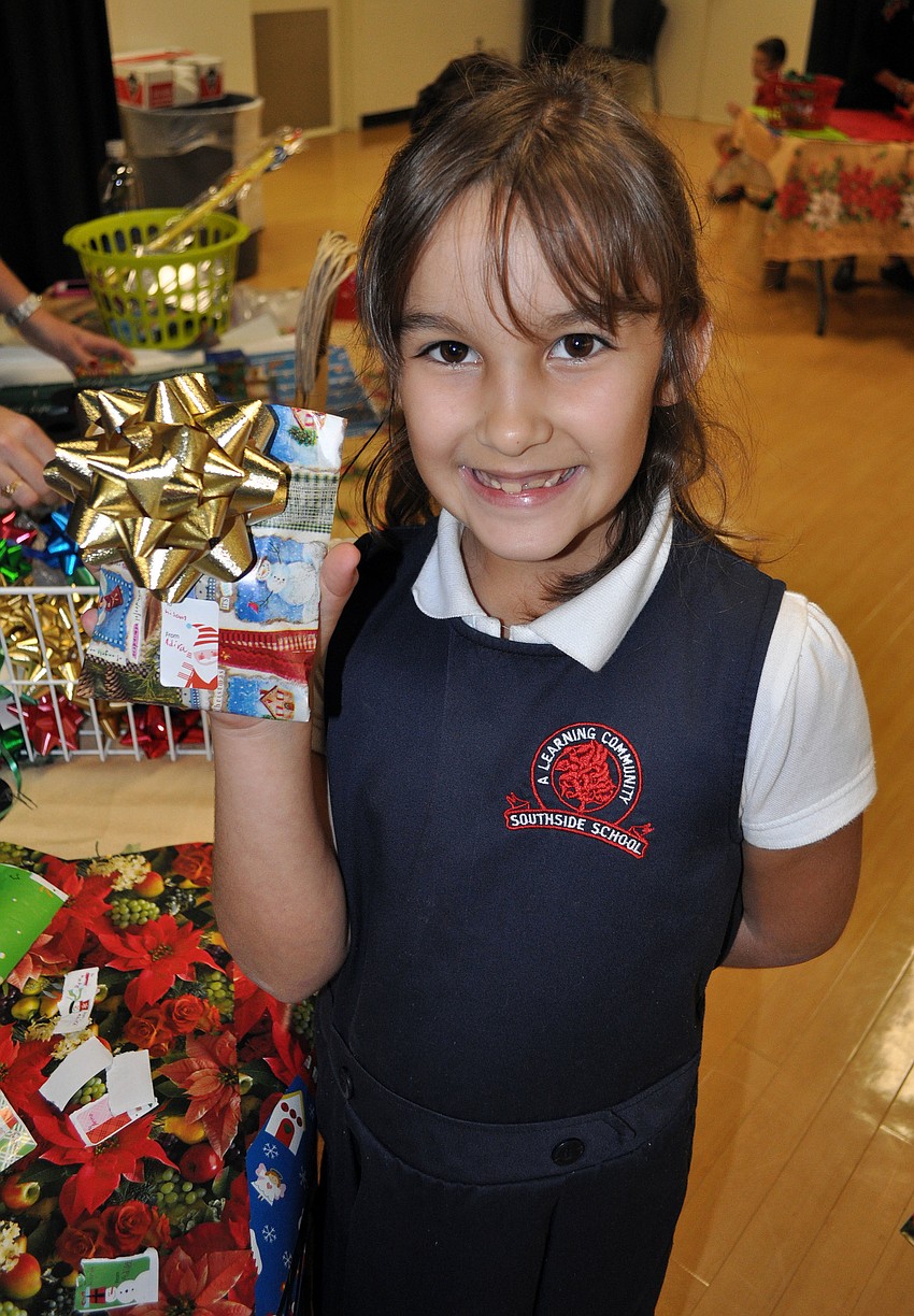 Adira Figueroa, 7, shows off the wrapped gift that she bought for her brother, Haisam, who is in the Army and will be home for the holidays and for good in two weeks.