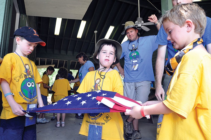 Six-year-olds Evan Fredd, Eric Brady and Conner Manrodt learn how to properly fold the flag, during Cub Scout Day Camp June 11-15, at Camp Flying Eagle. Published June 21, 2012.
