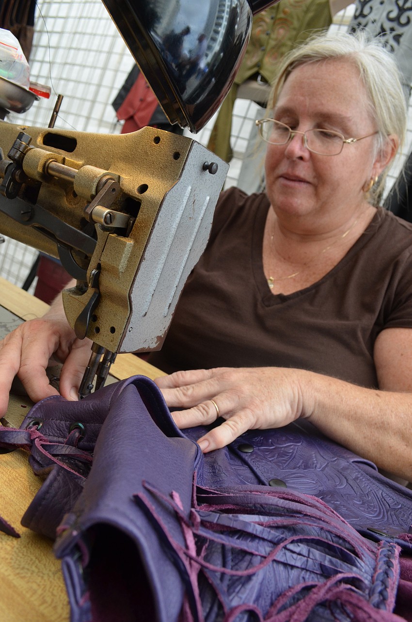 Barbara Krone sews a leather vest at the festival.