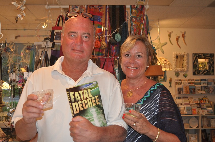 Tom and Susan Oâ€™Rourke, vacationing from Bloomington, Ill., pick up a copy of H. Terrell Griffinâ€™s â€œFatal Decreeâ€ while shopping at KKâ€™s Artique.