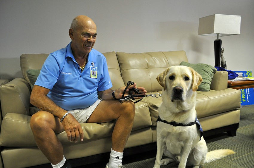 Mike Miller sits with Squire, a goldador.