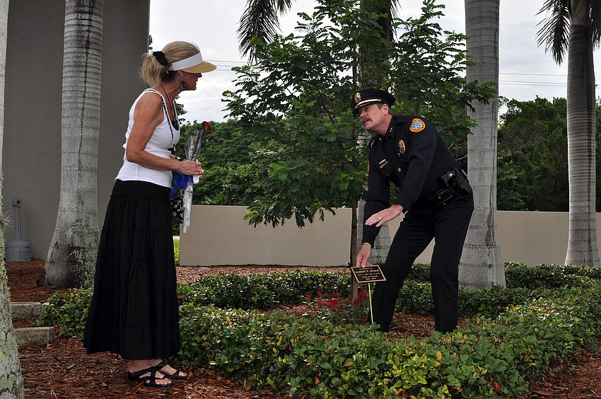 Longboat Key Police Chief Peter Cumming shows Leslie Hogle and the rest of the crowd where the plaque will be placed in front of the tree that was planted in honor of Al Hogle.