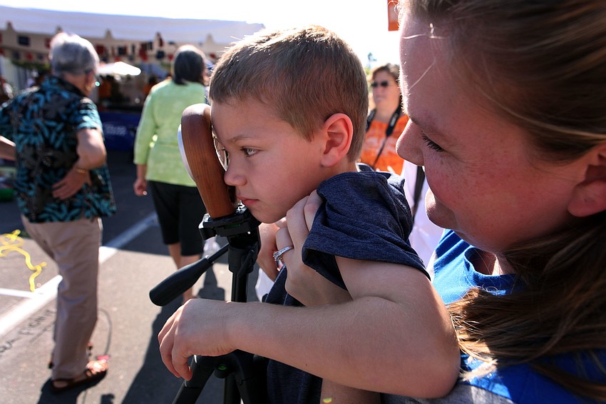 Valerie Glessing holds up her son Austin, 5, to look through a viewfinder to see a 3D chalk piece.